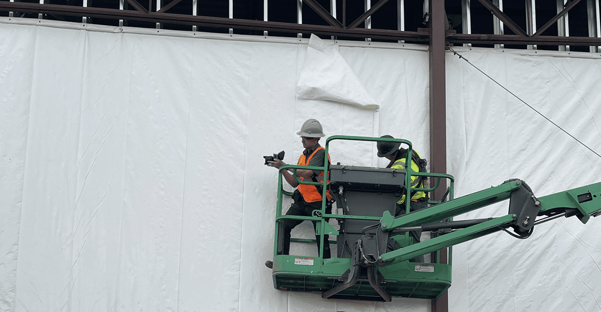 worker on lift installing dust containment wrap